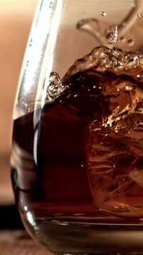 Ice falls into a glass of whiskey. Filmed on a high-speed camera at 1000 fps. High quality FullHD footage