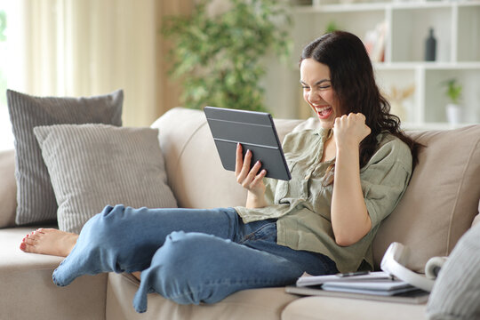 Excited student celebrating good news holding tablet