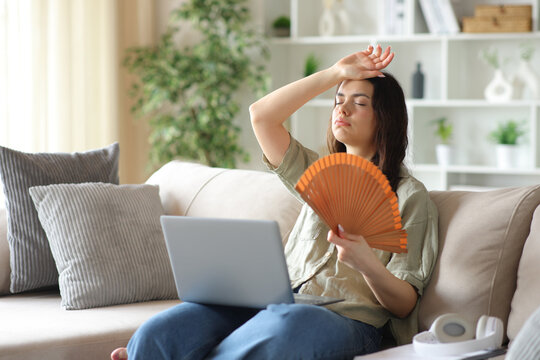 Young student suffering heat stroke fanning at home