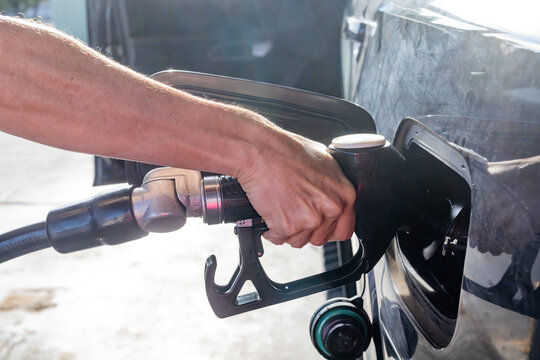 Hand of a woman at a fuel bowser filling a car with diesel