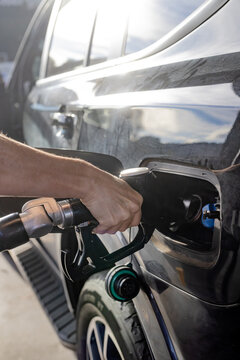 Hand of a woman at a fuel bowser filling a car with diesel