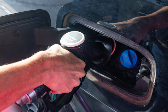Hand of a woman at a fuel bowser filling a car with diesel