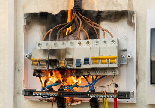 Electrical panel on fire in a home during the day causing smoke and damage to wires and circuitry