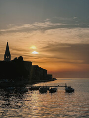 Obraz premium Sunset Over the Harbor with Silhouetted Buildings