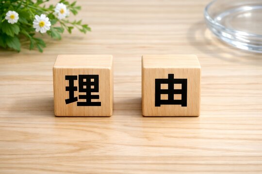 木の机に置かれた理由という漢字が書かれた積み木と白い花とガラスの皿がある無人の風景