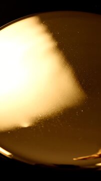 Thick golden engine oil pouring into a smooth pool.