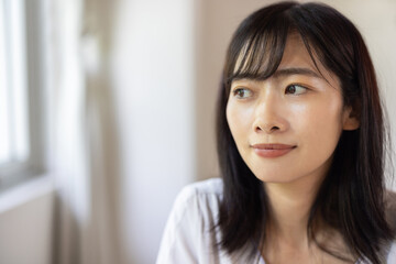 Obraz premium Young Asian woman gazing out of window