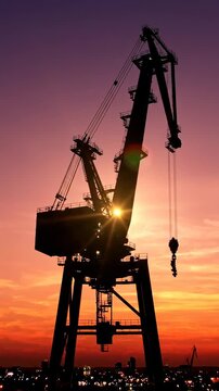 Industrial crane at sunset silhouette.