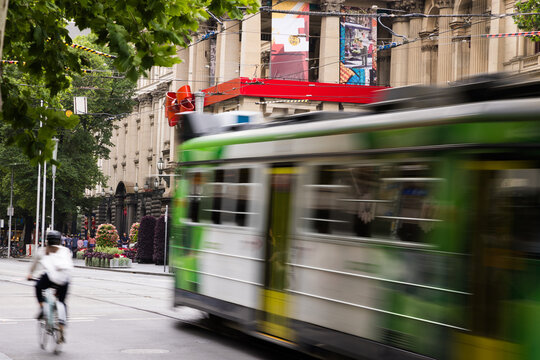 Green and white tram rushes past on a city street captured with motion blur