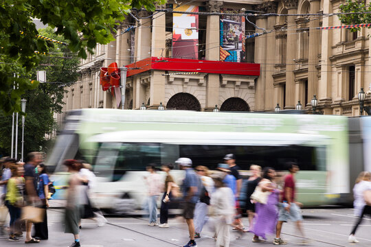 Green and white tram rushes past on a city street captured with motion blur