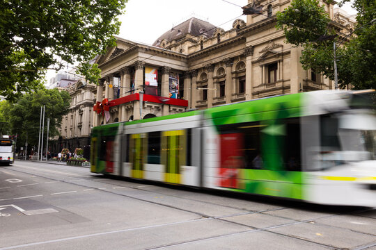 Green and white tram rushes past on a city street captured with motion blur