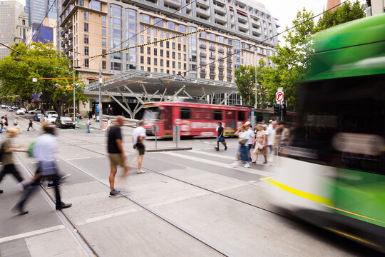 Green and white tram rushes past on a city street captured with motion blur