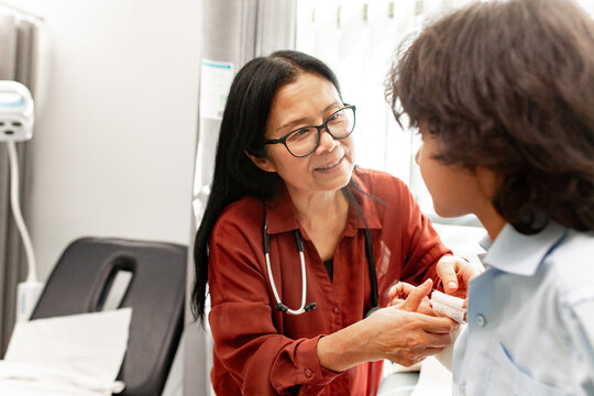 Doctor checking patient&rsquo;s bandaged wrist in clinic