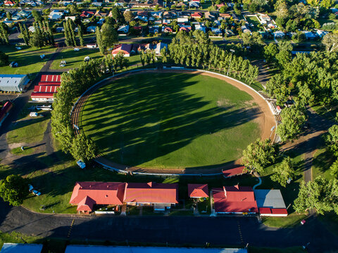 Buildings around Glen Innes Showground ring in bright sunlight from aerial view