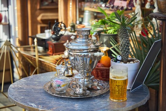 Still life on a table in an outdoor cafe. Traditional Russian samovar and a glass of beer