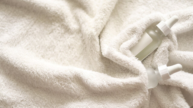 Serene Skincare Setting With Dropper Bottles, The serums are wrapped in a white terry towel.