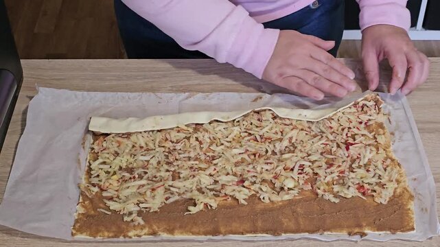 Woman's hands rolling homemade apple strudel dough