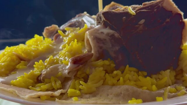 Extreme close up of hot steaming mansaf dish with yellow rice and lamb meat