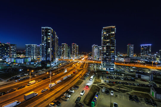 night panorama of light in windows of multistory building. life in a big city with a wide highway and the light from car headlights