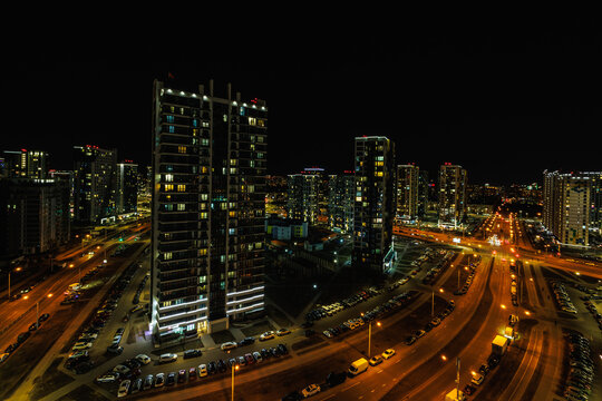 night panorama of light in windows of multistory building. life in a big city with a wide highway and the light from car headlights