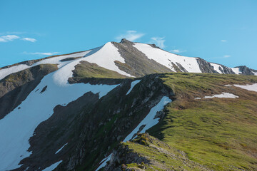 Scenic view above rocky ridge with cliff and snows against pointy peak. Alpine scenery with sharp rocks, sheer crags and peaked top. Tectonic plate protruding from an abyss. Stony pointed pinnacle. © Daniil