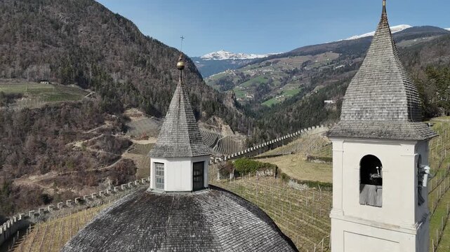 Orbital Drone Flight Between Twin Church Domes with South Tyrol Alps and Vineyards in Chiusa, Italy