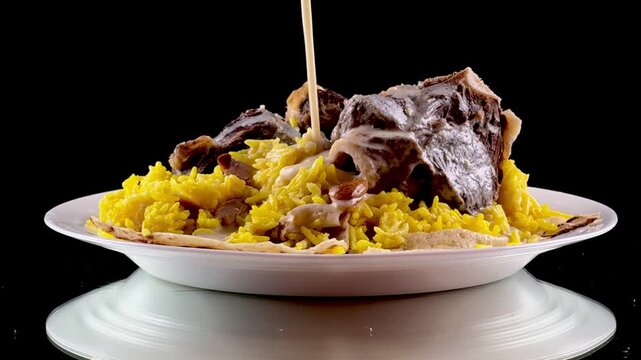 Cinematic close up of pouring traditional jameed yogurt sauce over mansaf jordanian arabic food