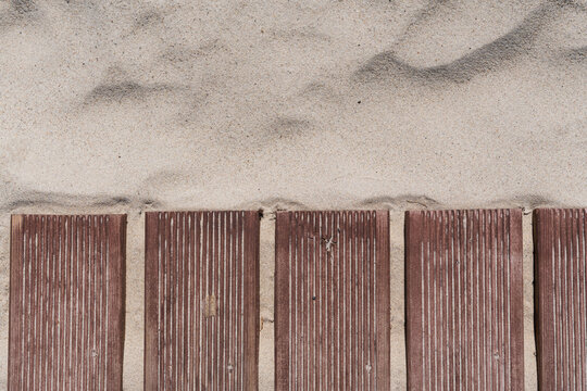 High angle view of wooden boardwalk meet sand on Parnu beach in Estonia with natural stone and visit parnu metal plaque on a sunny summer day