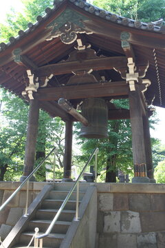 A traditional wooden bell tower (Shoro) surrounded by lush greenery at a Japanese temple.