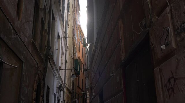 Sunbeam entering dark medieval alley, Genoa caruggi, Italy