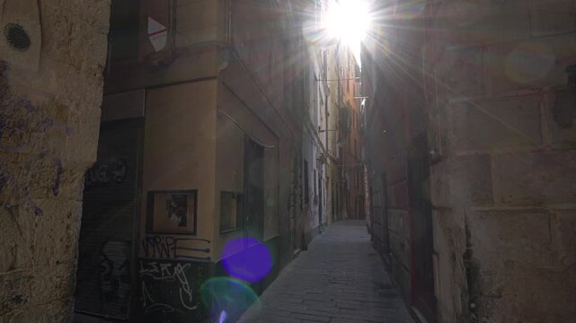 Sunlight ray through narrow alley in Genoa historic center, Italy