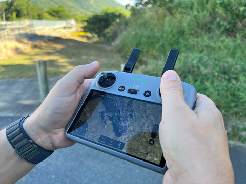 Hands Holding Drone Remote Controller with Live Video Feed of a Crocodile