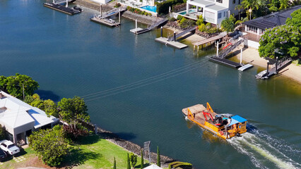 Aerial View of Maintenance Boat Navigating Gold Coast Residential Canal © blueringmedia