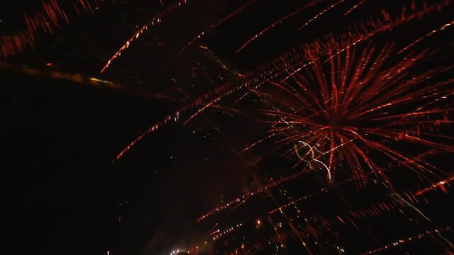 FPV aerial view of colorful fireworks exploding with bright trails in the dark night sky over Novi Sad, Vojvodina, Serbia.