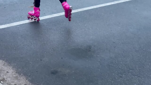 Cropped shot of child inline skating on wet asphalt