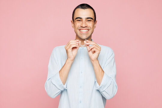 Young toothy smiling happy excited middle eastern man wear blue shirt point index fingers on opened mouth teeth isolated on plain pastel light pink wall background studio portrait. Lifestyle concept.