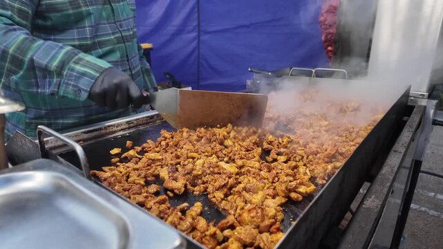 Fresh seasoned chicken cooks on a hot flat-top grill at a busy street taco stand as steam rises, capturing authentic street food preparation and outdoor culinary culture