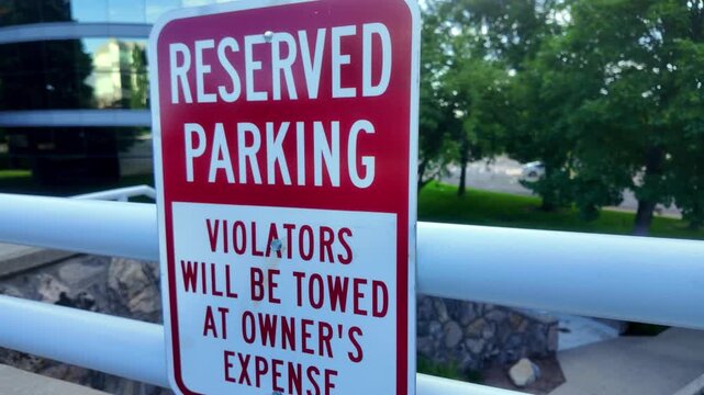 Reserved Parking Violators Will Be Towed At Owner&rsquo;s Expense Red and White Sign with Business Complex Buildings in background uneasy feeling side angle view