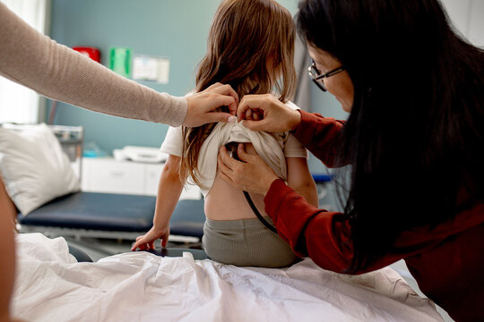 Asian paediatrician examining the little girl using stethoscope