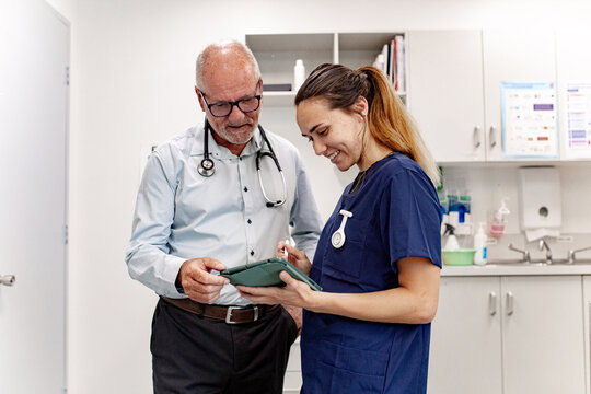 Doctor and nurse collaborating while reviewing information on a tablet