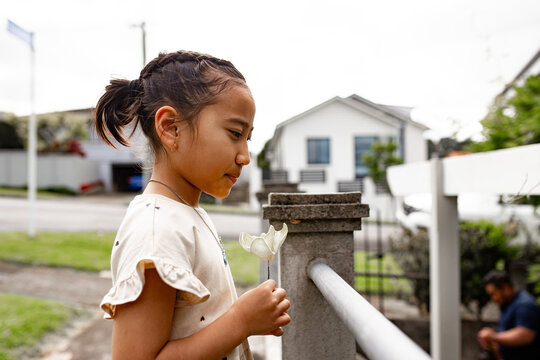 Young Samoan girl holding a white flower outdoors