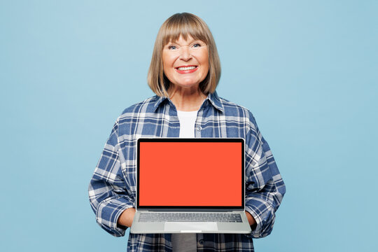 Elderly blonde smart IT woman 50s years old wear checkered shirt casual clothes hold use work on blank screen area laptop pc computer isolated on plain pastel blue background studio Lifestyle concept