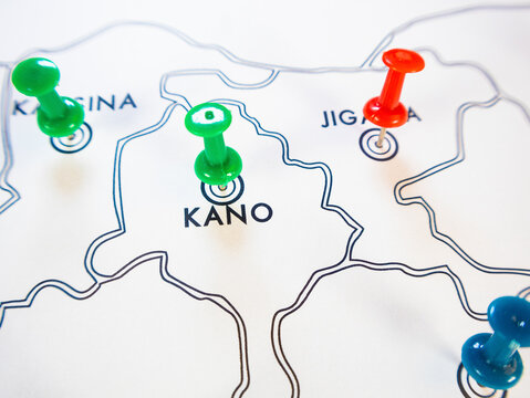 A white paper map of northern Nigeria shows location markers. Green pins mark Kano and Katsina, a red pin marks Jigawa, and a blue pin sits in the corner, representing logistics, travel, or data track