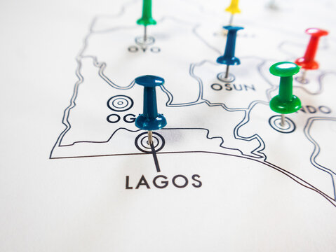 A close up shot of a white Nigerian state map. Brightly colored pushpins blue, green, and red mark specific southwestern states including Lagos, Osun, Oyo, and Ondo.