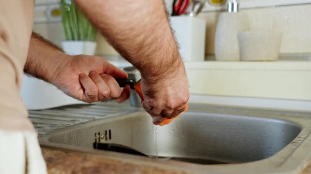 Person cleans kitchen knife sharpener under running water in home sink