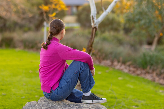 young woman sitting in park looking away