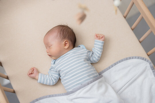 Gentle infant resting inside cozy wooden crib