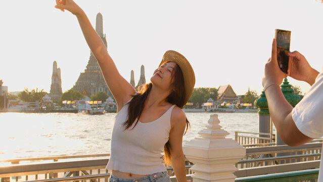 Young Woman Posing for Smartphone Photo by Wat Arun at Sunset