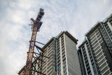 Fototapeta premium Tower Crane and High Rise Building Construction Against Blue Sky
