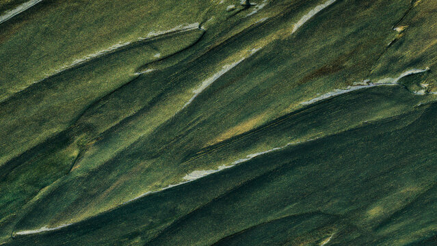 Abstract dark green paint texture background with gold metallic brush strokes and shimmer